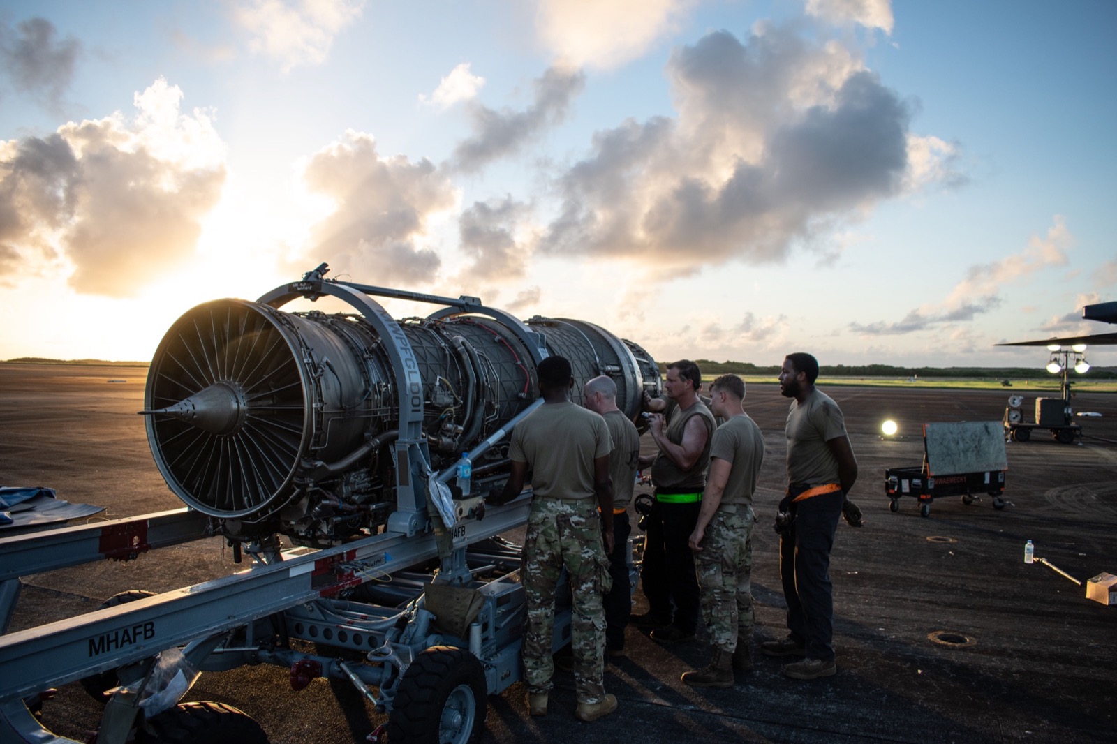 Maintainers working around an F-15 engine at sunset